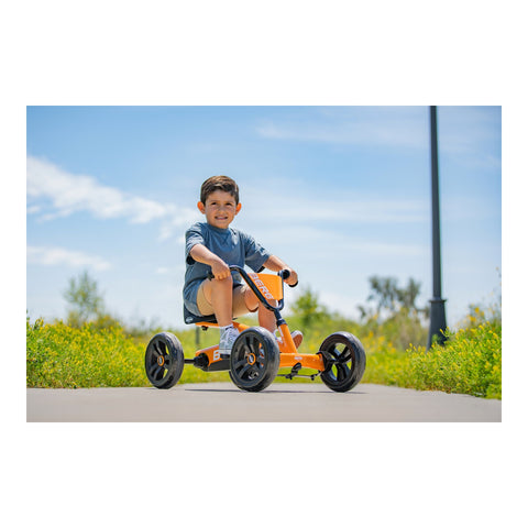 Child riding a BERG Buzzy Orange pedal kart